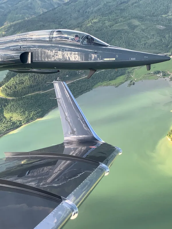 S-211 in formation over a green mountain lake