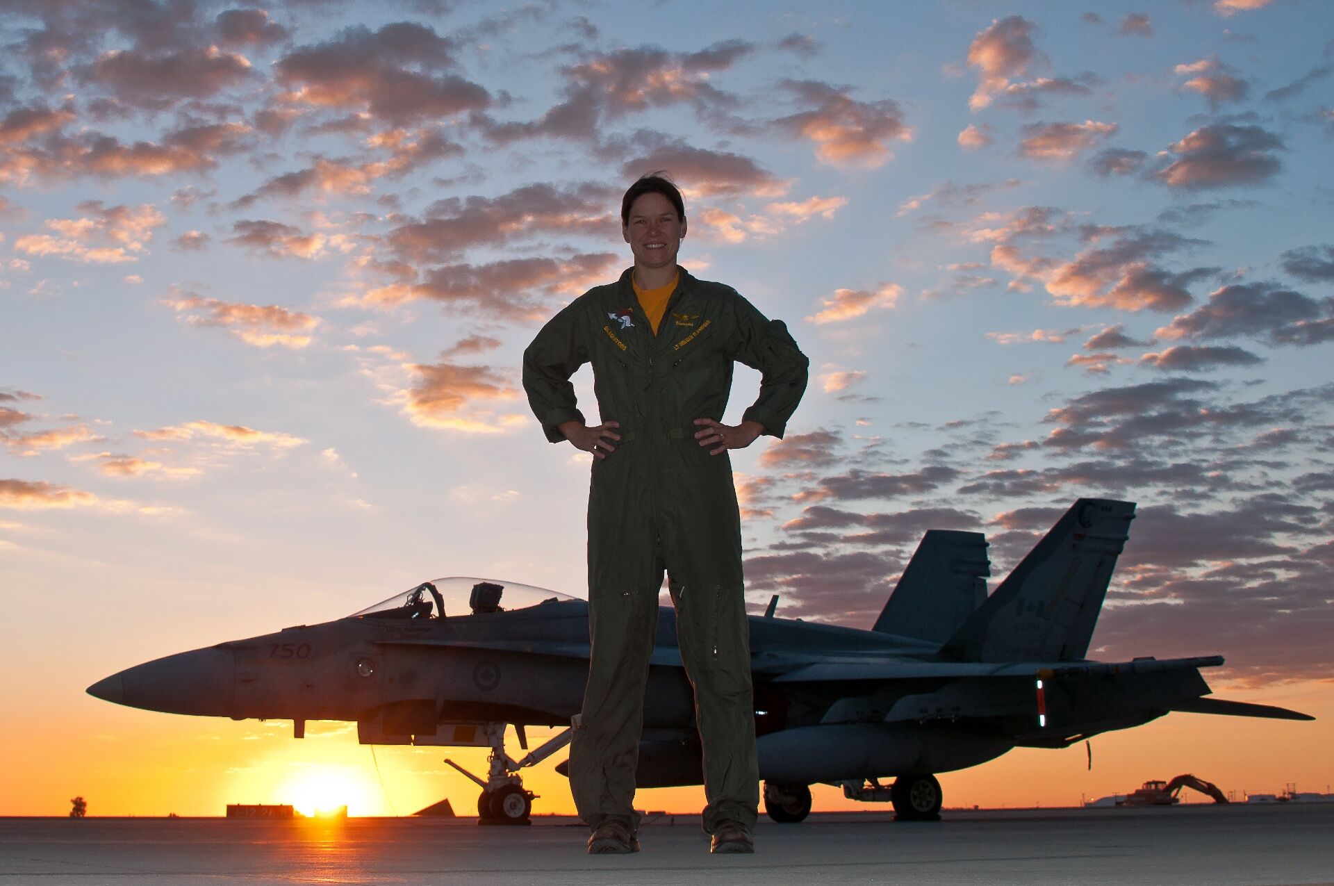 Meagan Flannigan standing in front of a fighter jet at sunset